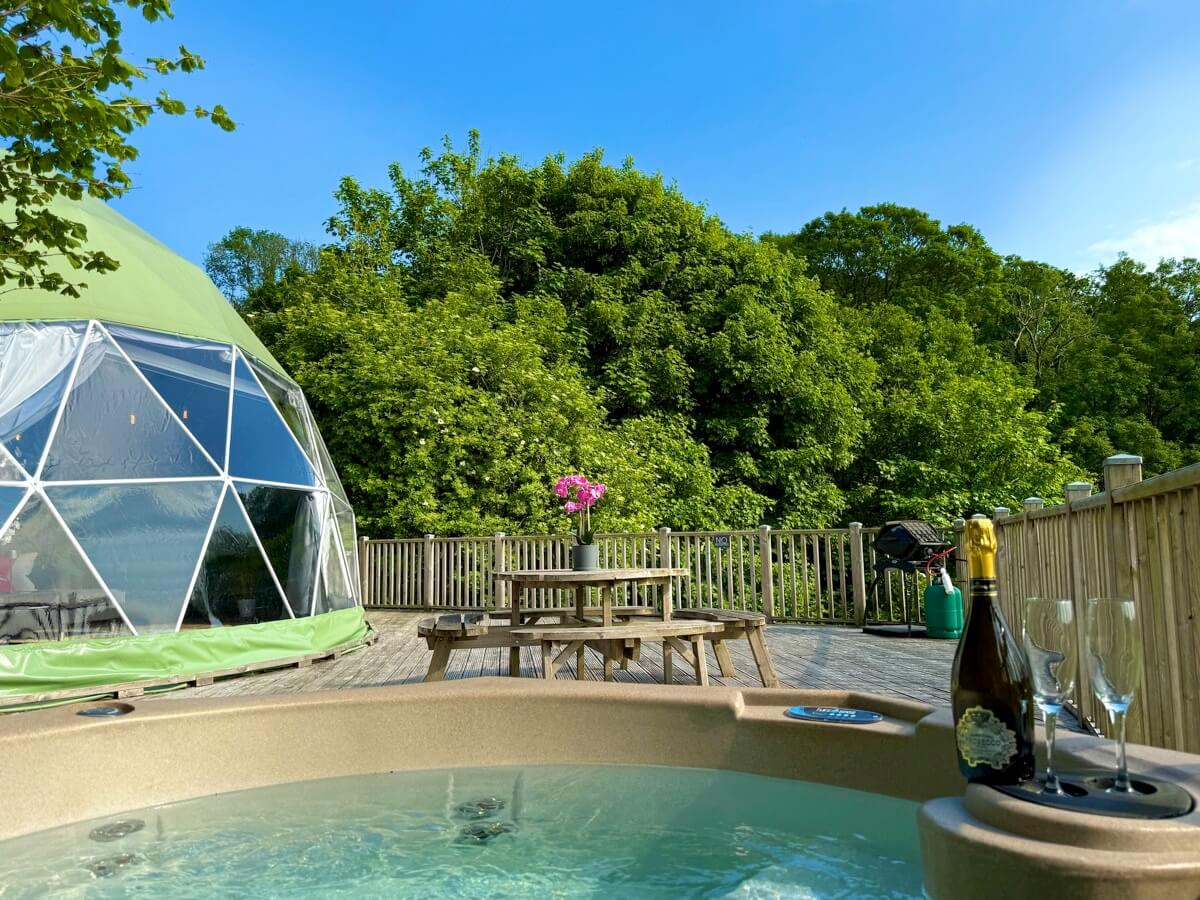 Clear day showing dome, hot tub, and open pasture beyond
