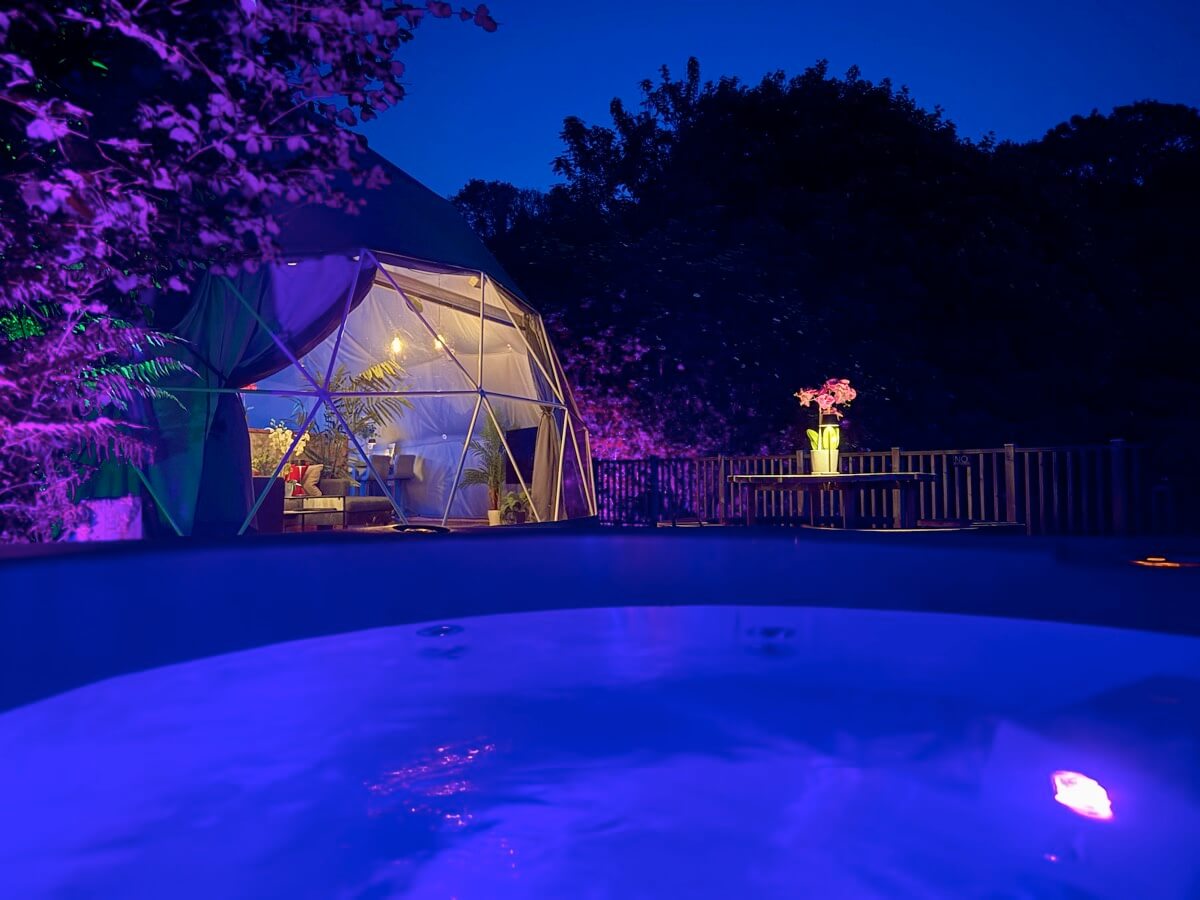 Private hot tub glowing at night beside the dome