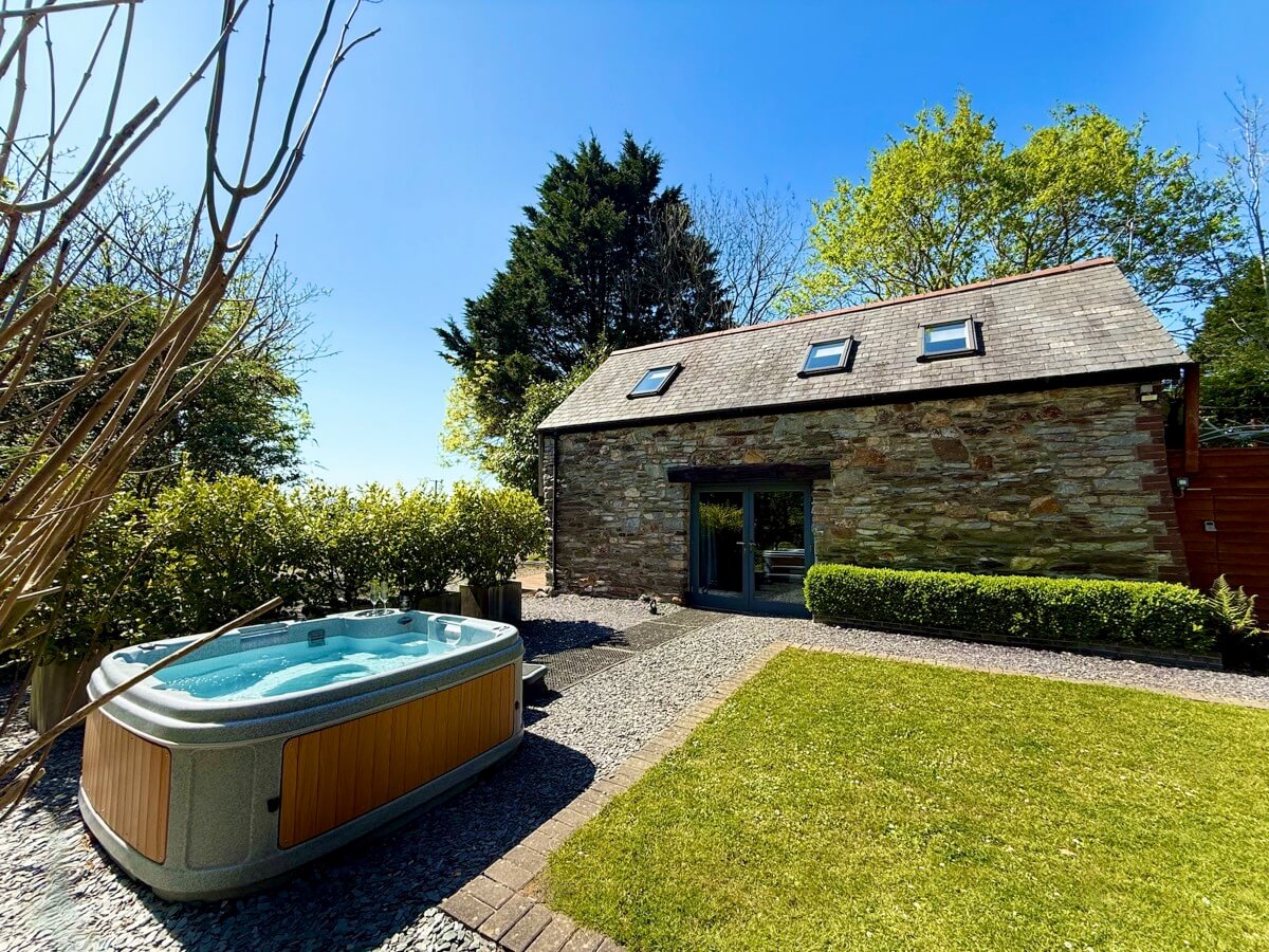 Sunridge Lodge and hot tub by day, surrounded by greenery.