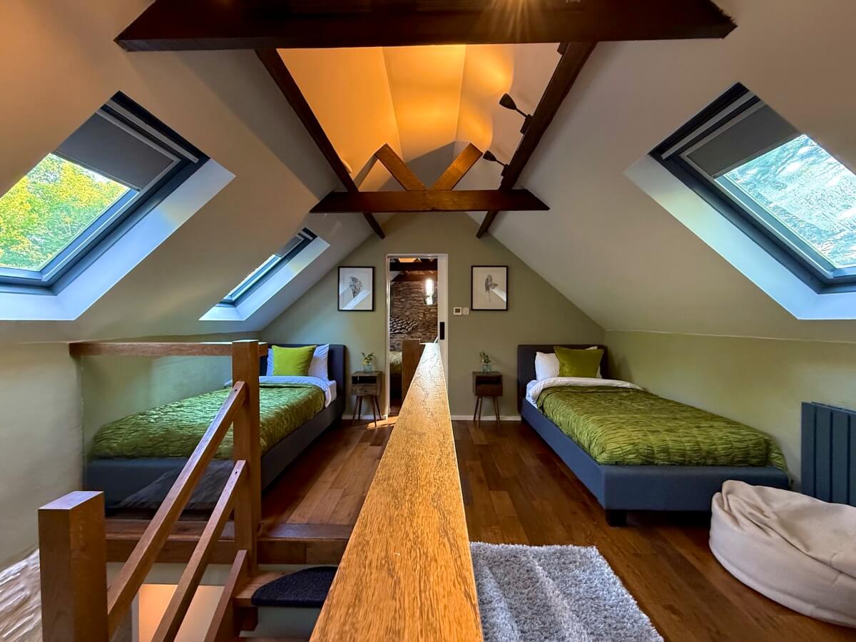 Bright twin bedroom with skylights and wooden beams.