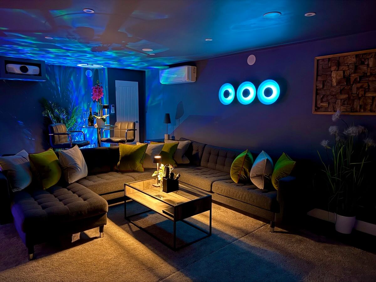 Cosy corner of cinema room with mood lighting and green cushions.