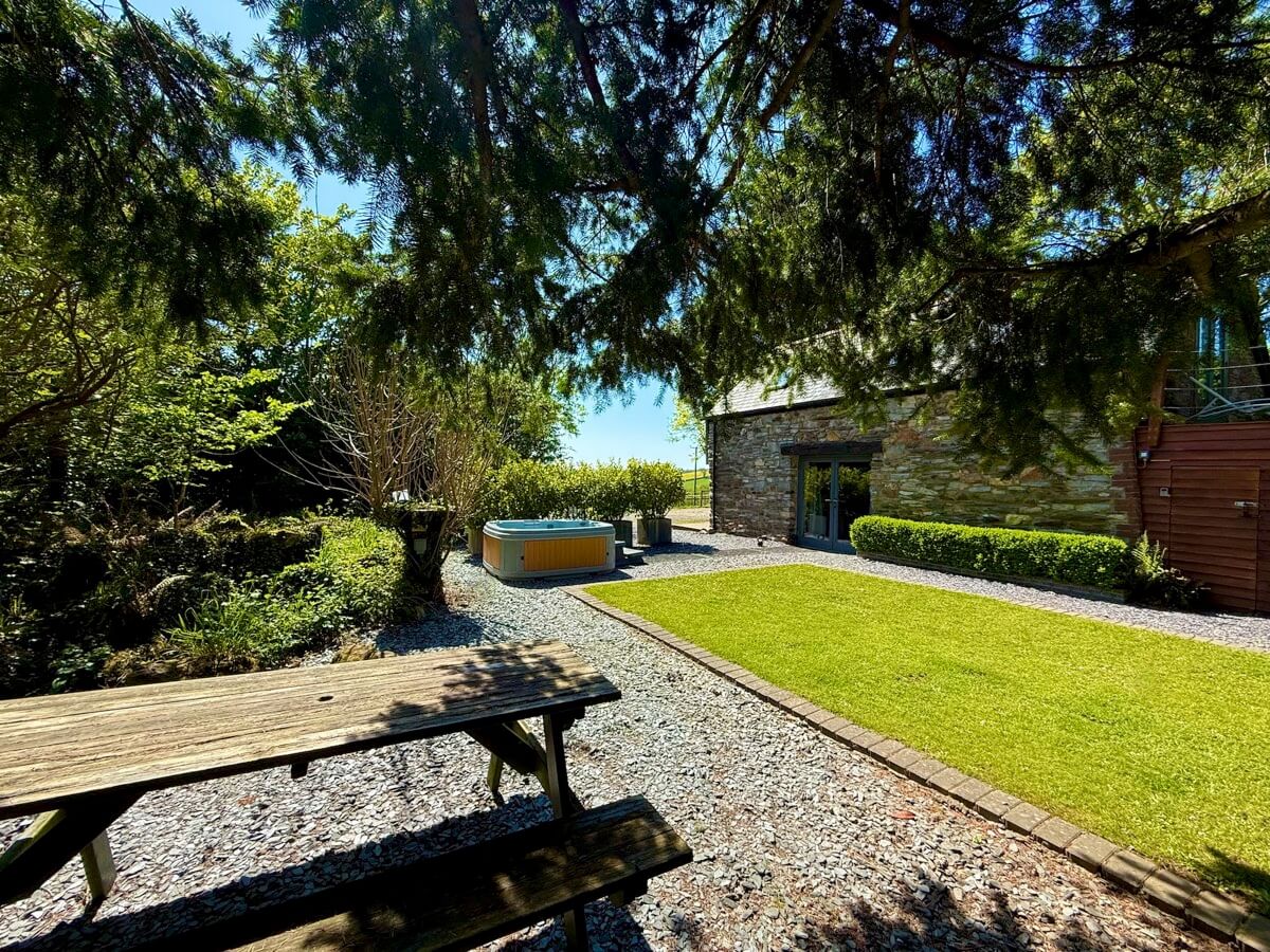 Lawn and picnic area with hot tub nestled under the trees.