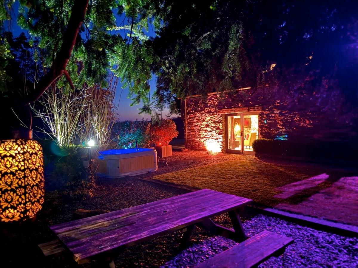 Magical garden lighting and glowing hot tub at dusk outside Sunridge Lodge.