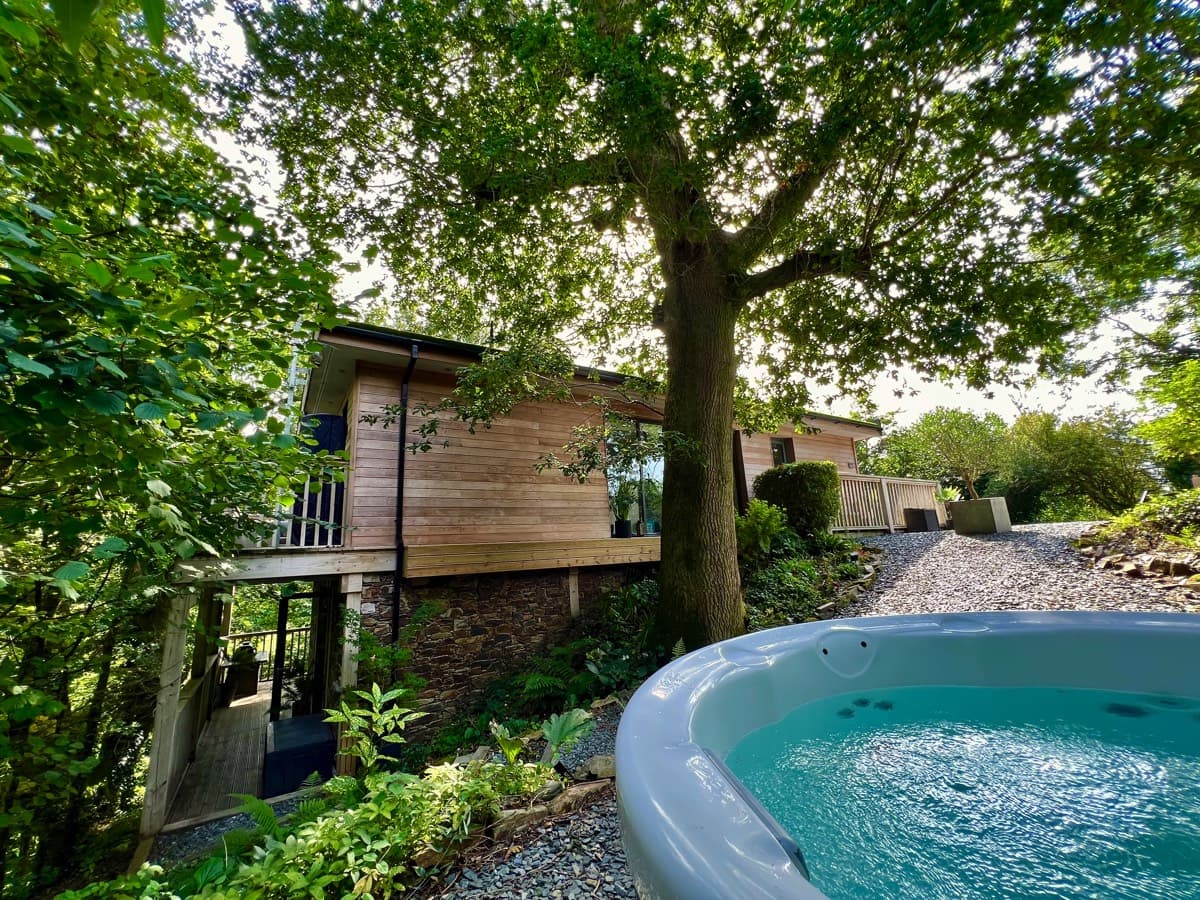 Lavish treehouse facade with a modern hot tub, blending luxury with nature.