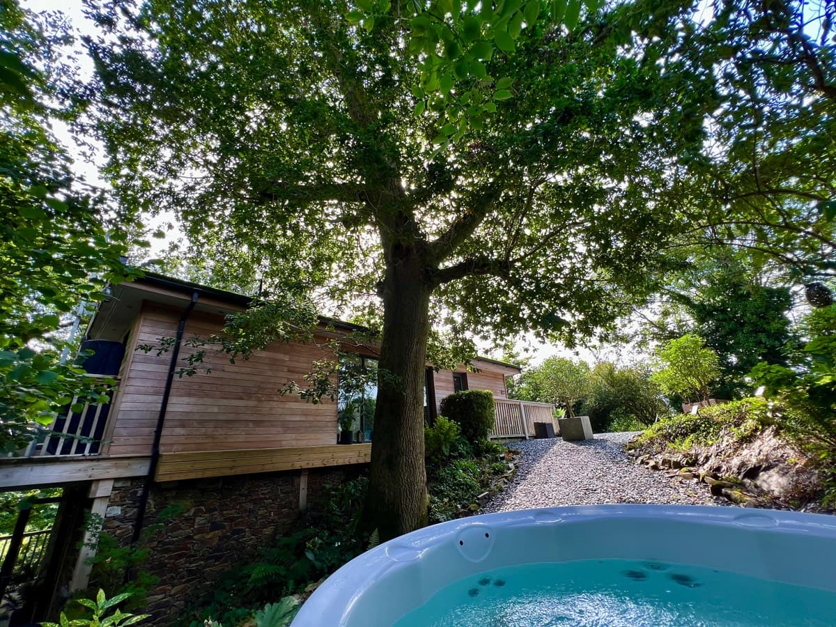 Tranquil treehouse setting in Devon, front view showcasing a hot tub for relaxation.