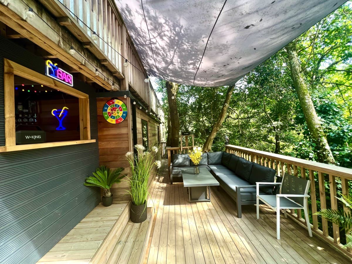 Lower deck bar set against a backdrop of serene woods, perfect for daytime gatherings.